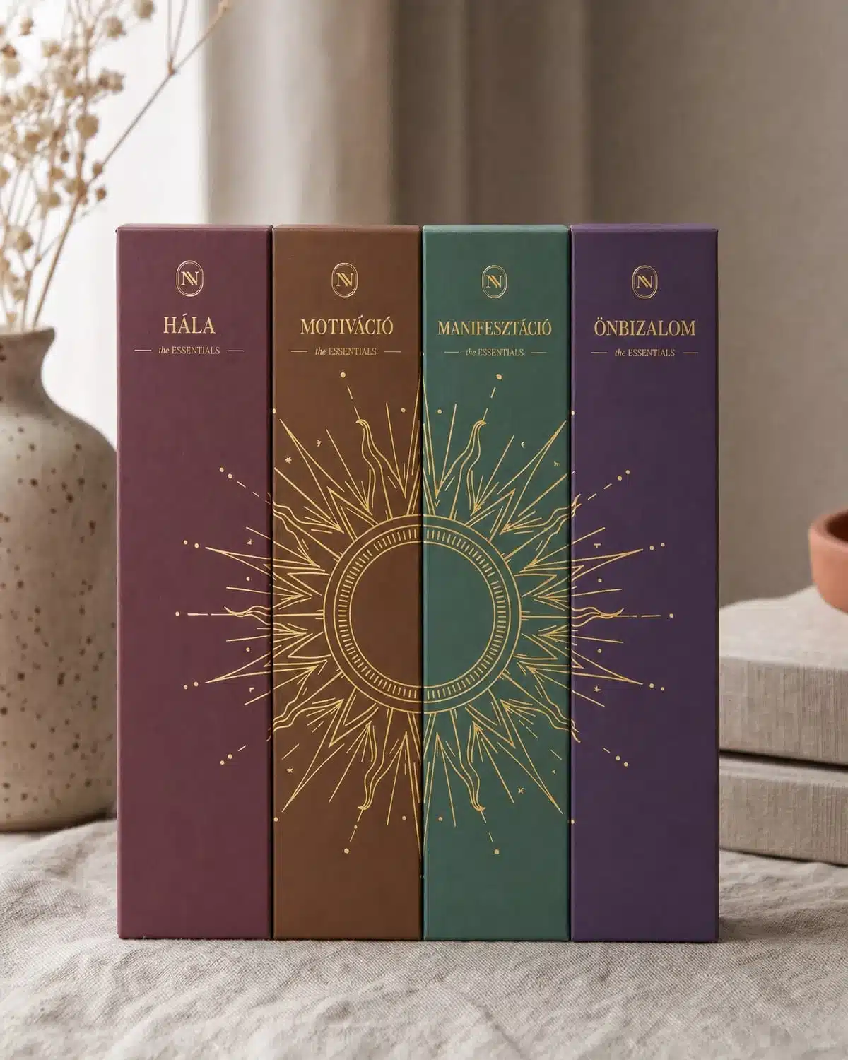 A négy the ESSENTIALS doboz egymás mellett, a gerinceken összeálló napmotívummal